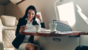 Business woman with dak hir sitting at the table of a private jet looking at some documents.